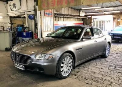 Maserati Quattroporte grise sur l’allée pavée du garage Autorosati