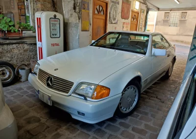 Mercedes SL R129 blanche devant pompe à essence vintage