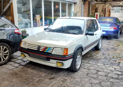 Peugeot 205 GTI 115cv blanche à l’entrée du garage Autorosati