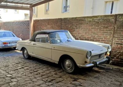 Peugeot 404 Cabriolet blanc cassé devant mur de brique
