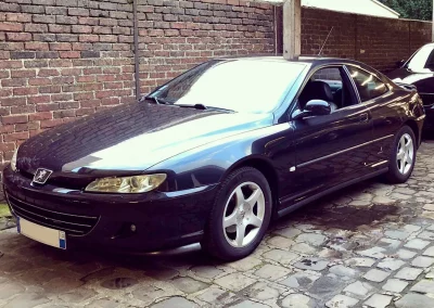 Peugeot 406 Coupe bleu devant mur de briques rouges
