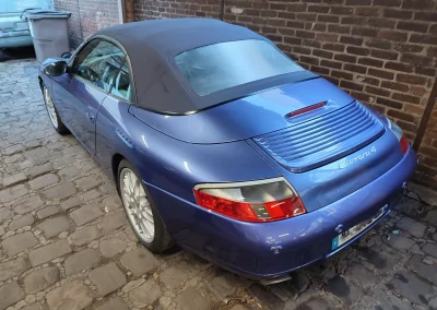 Porsche 911 996 Cabriolet Carrera 4 bleue devant le mur de brique de l’atelier Autorosati