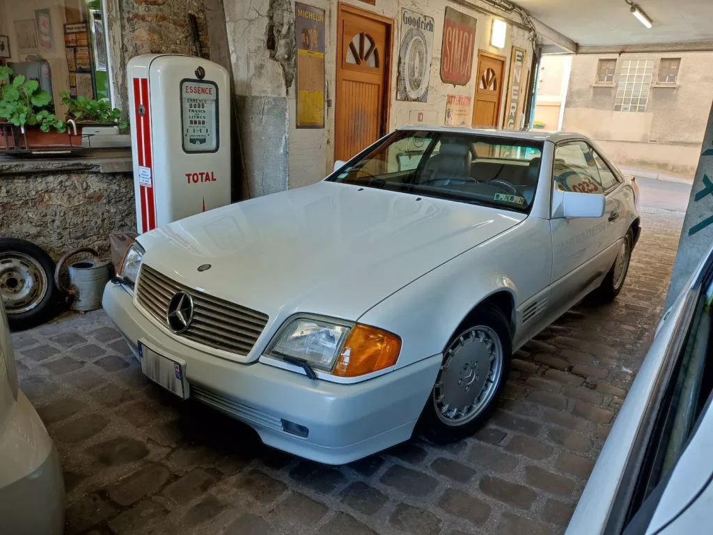 Mercedes SL R129 blanche devant pompe à essence vintage