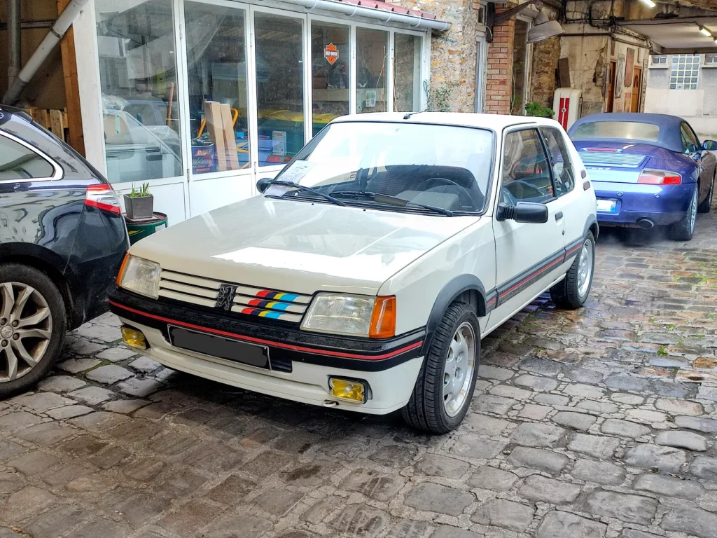 Peugeot 205 GTI 115cv blanche à l’entrée du garage Autorosati