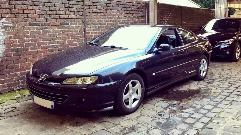 Peugeot 406 Coupe bleu devant mur de briques rouges